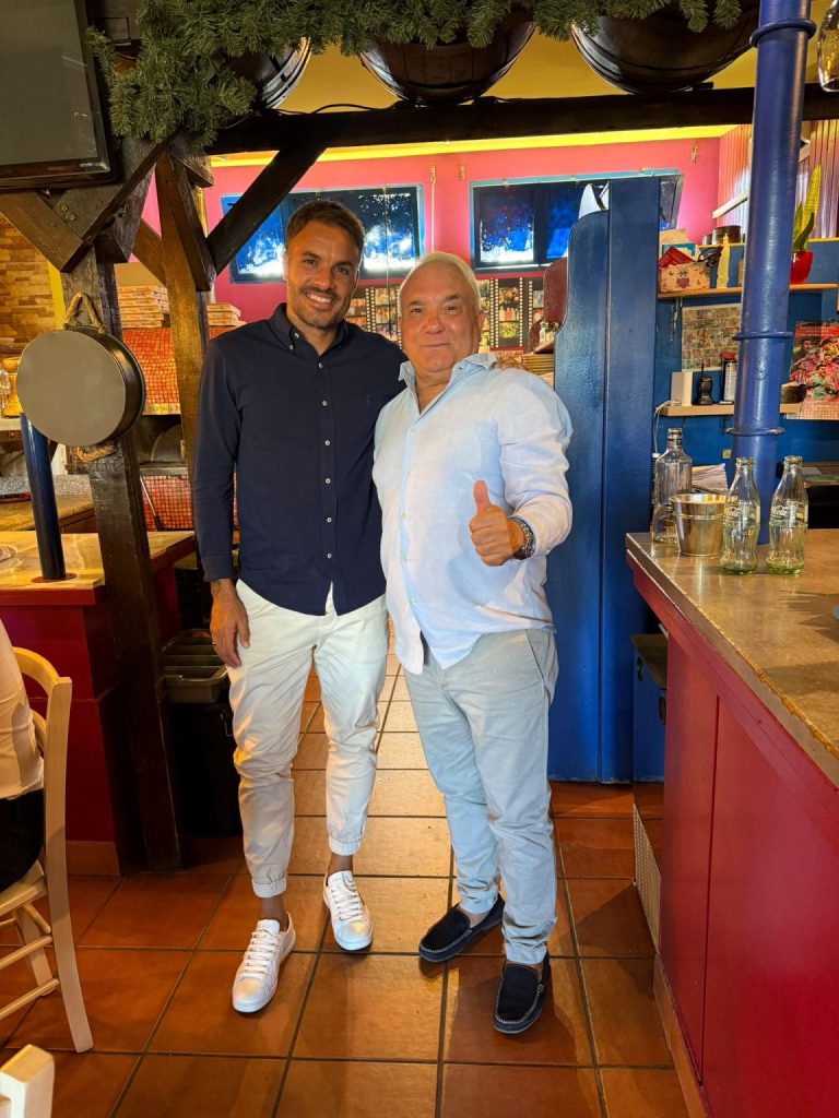 Dos personas posan junto a la barra y el horno de Bella Napoli