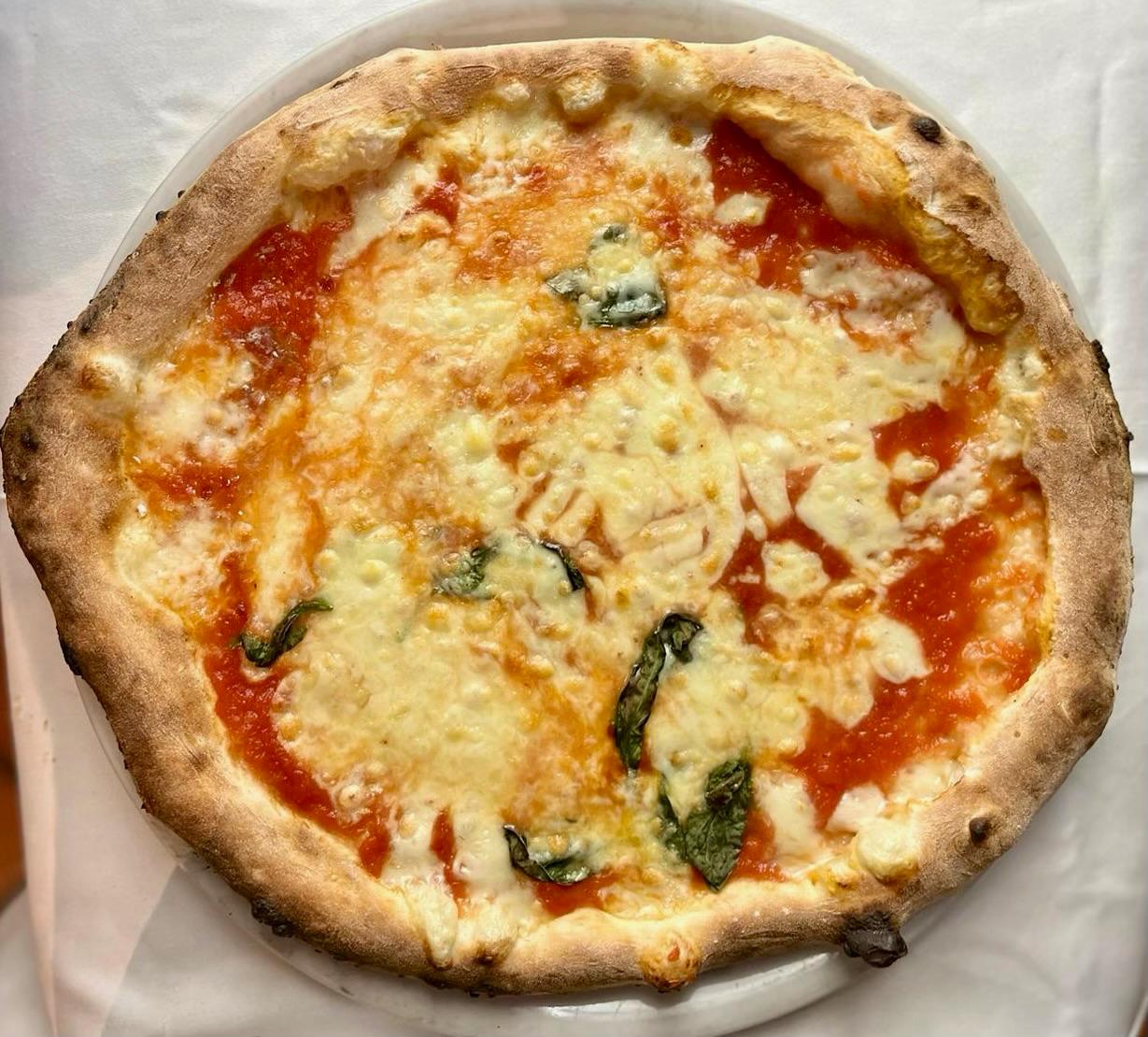 Pizza de Bella Napoli con tomate, queso y albahaca