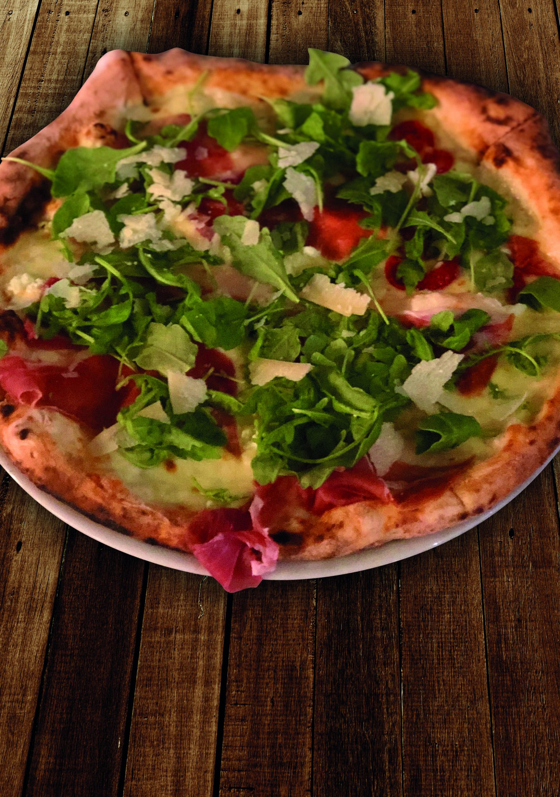 Una de nuestras pizzas, con rúcula y lascas de queso, sobre una mesa de madera